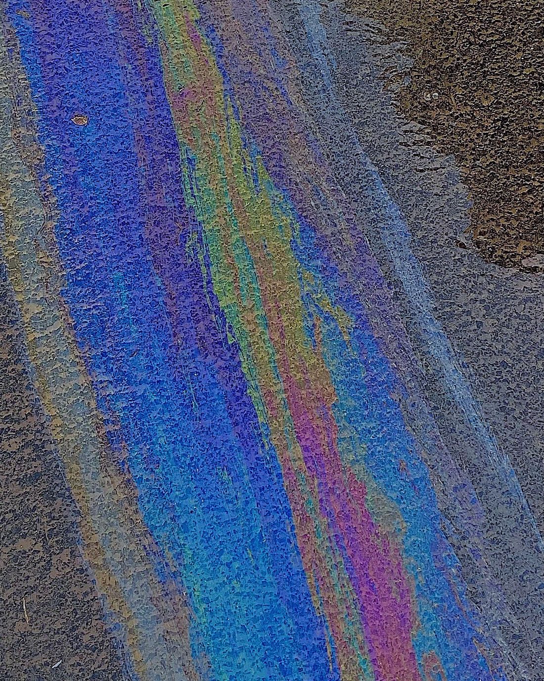 Iridescent oil sheen in a puddle on asphalt